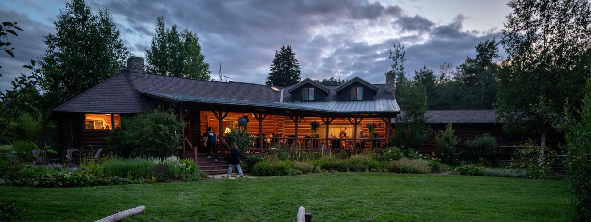 A group of people standing outside of a log cabin.